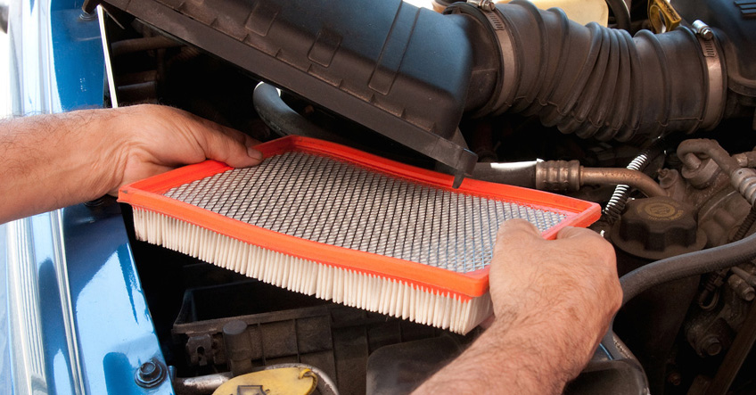 Person changing an air filter on an automobile.
