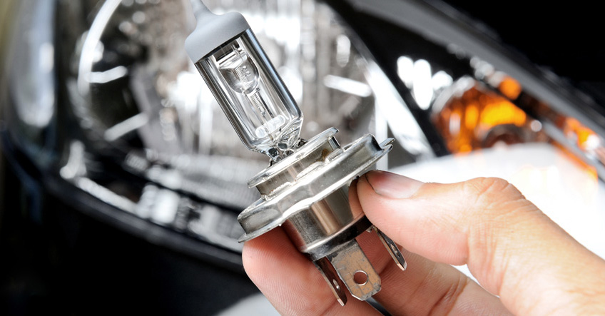 Person holding an halogen bulb from a car headlight system